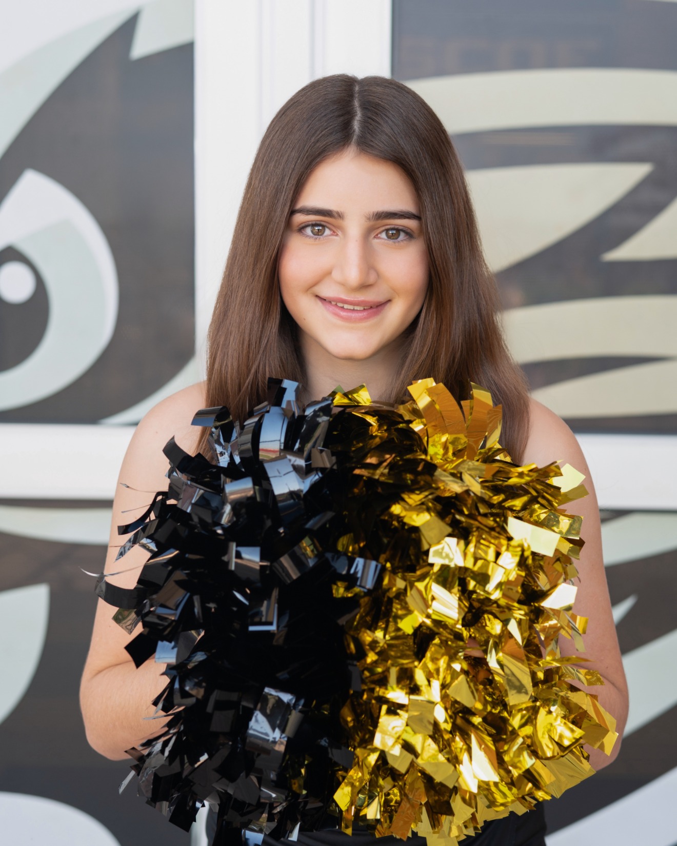 Tara, founder of Pom Pom Perfume, holding black and gold pom poms